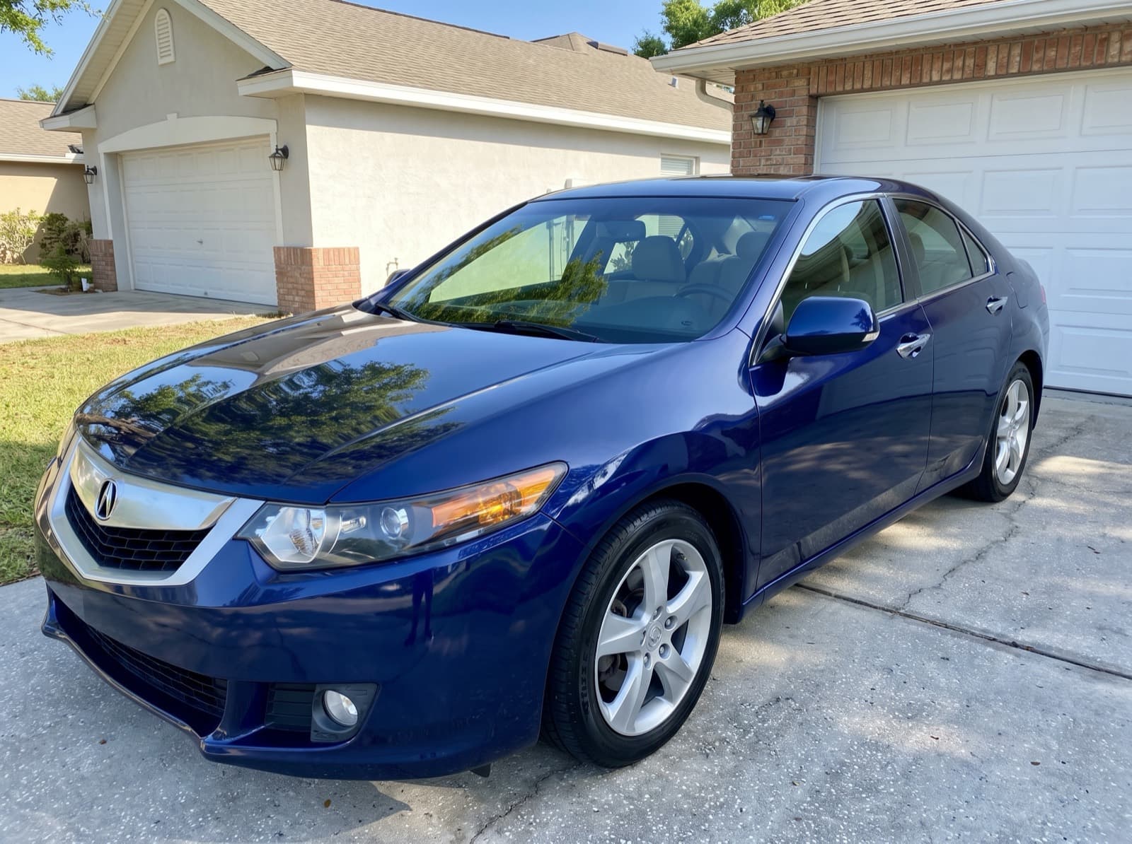 A dark blue sedan in front of a garage in Apopka, FL, after a Bang AutoGlass mobile glass job
